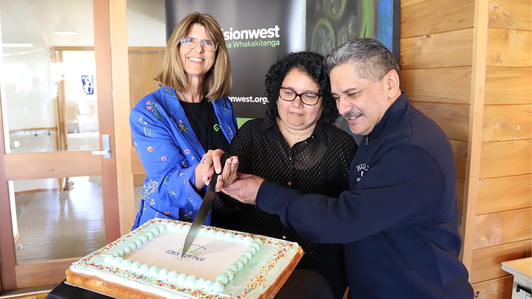 Three people cutting cake